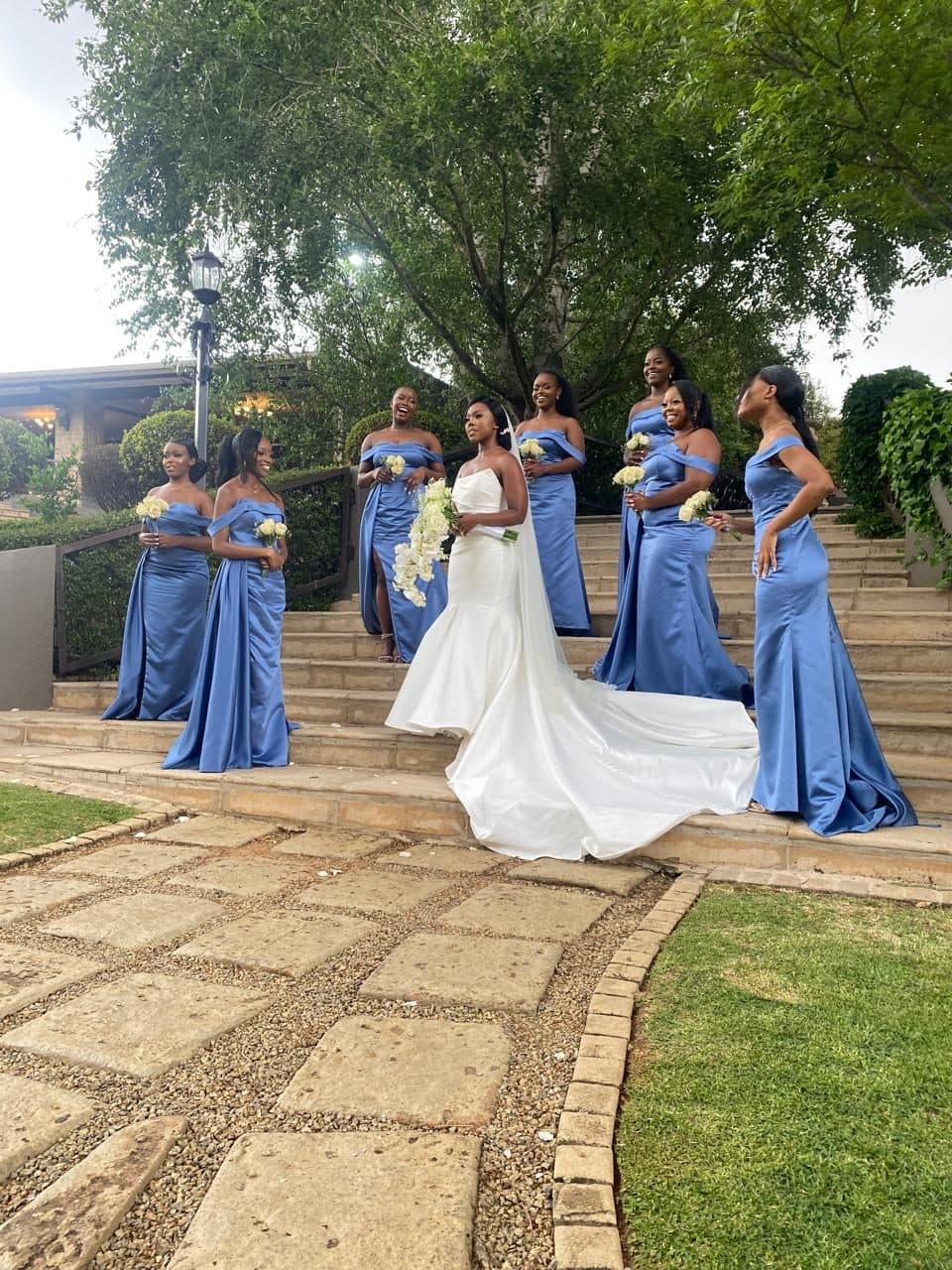 Bride with her bridesmaids in cornflower blue satin on the garden steps