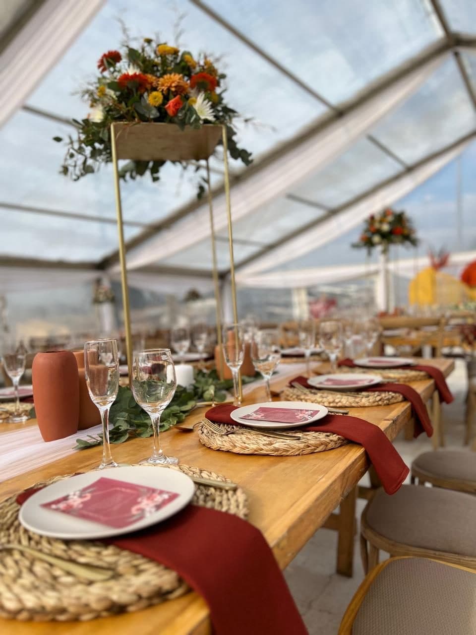 Long wooden banquet table with woven placemats and burgundy napkins