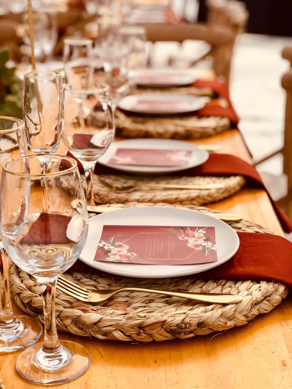 Row of place settings with gold cutlery and rust-toned linen