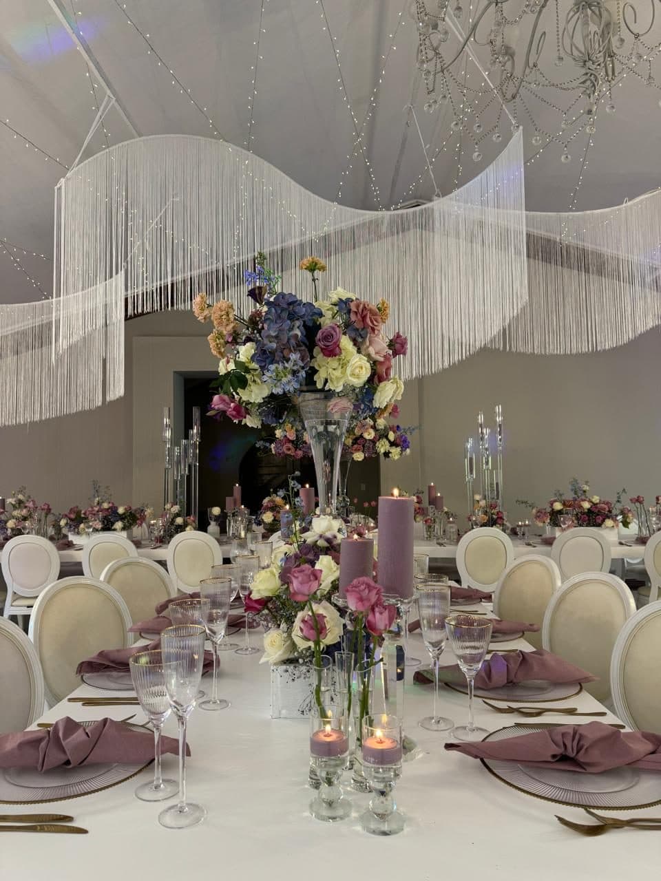 Pastel tablescape with a raised centrepiece under a fringed ceiling installation