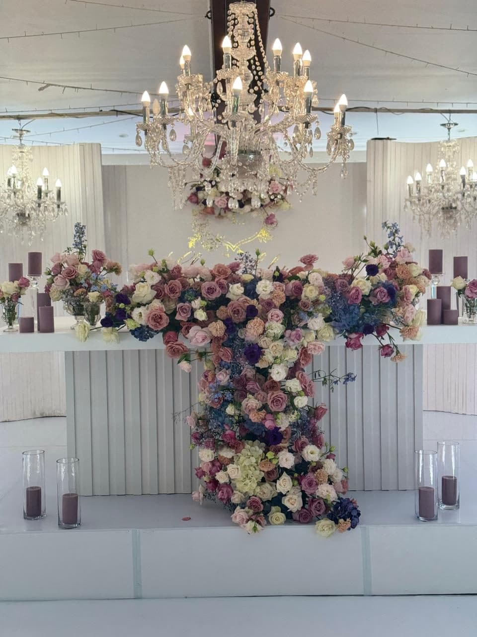 Main table with a cascading pastel rose installation beneath a crystal chandelier