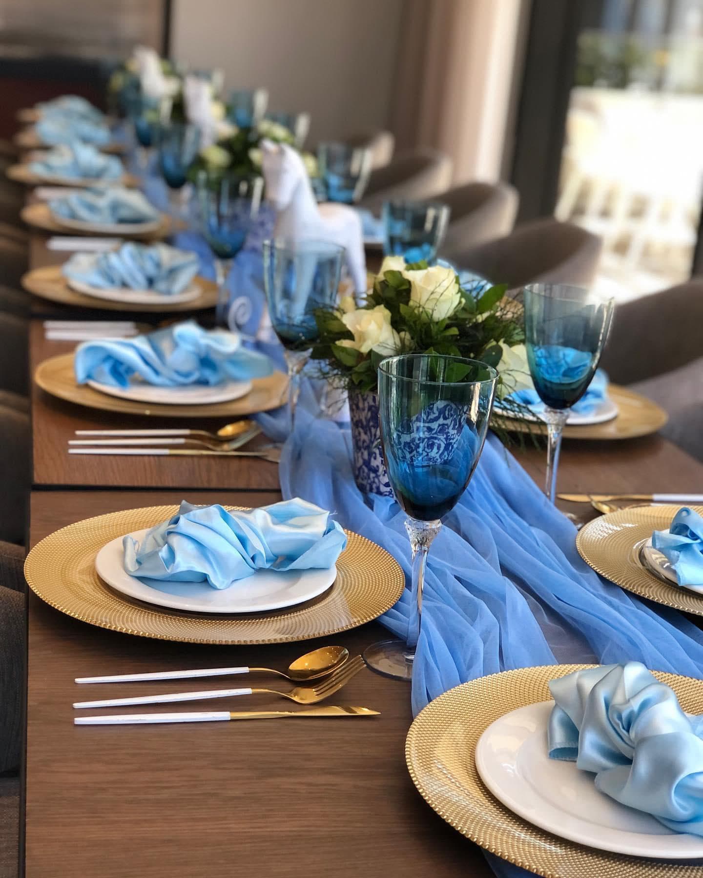 Blue and gold tablescape with charger plates and satin napkins
