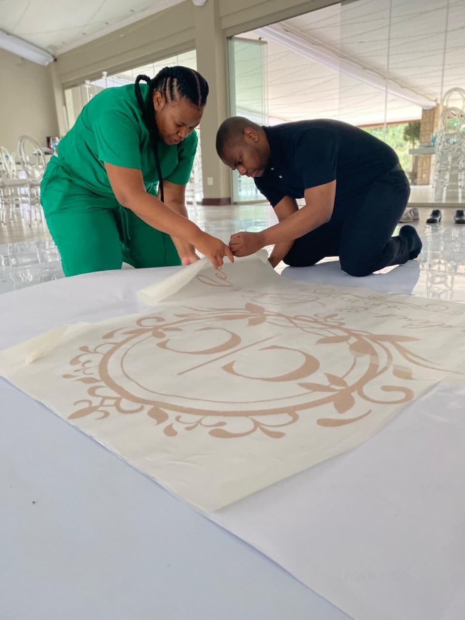 The Kuhle team applying a custom monogram decal to the dance floor before guests arrive