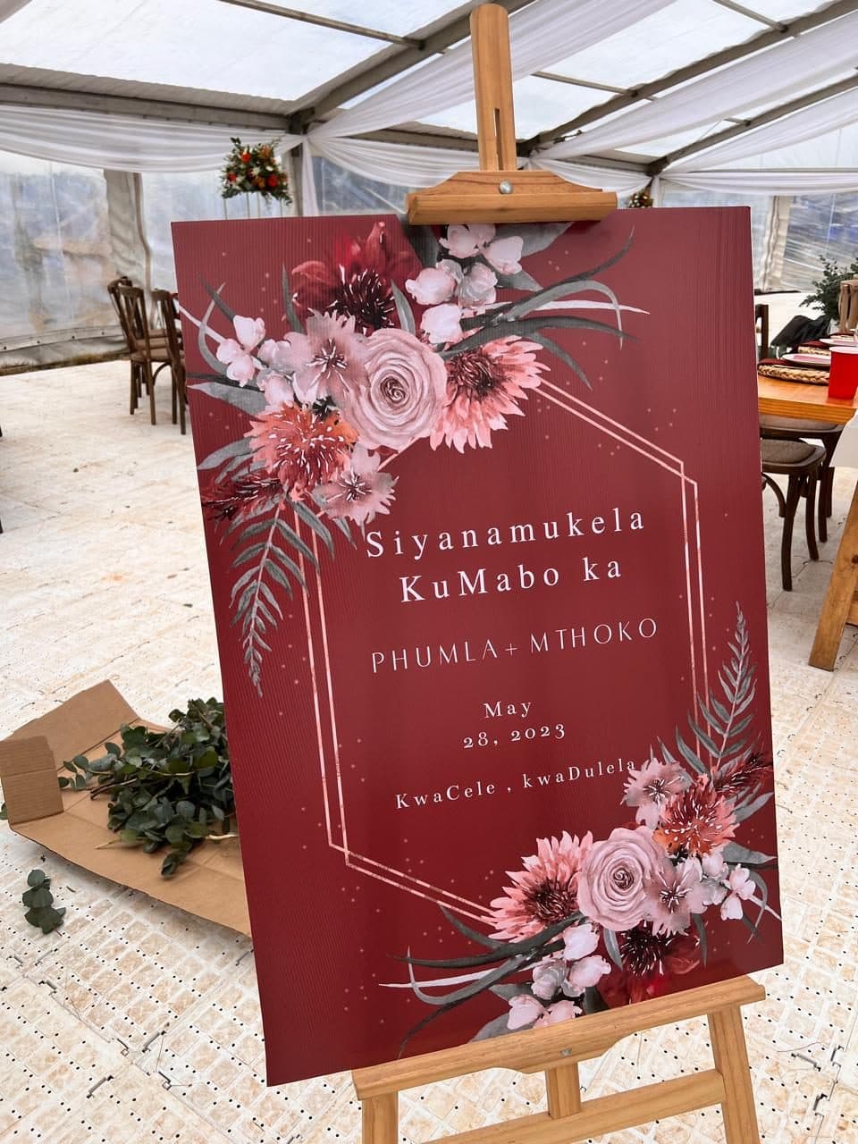 Burgundy welcome signage for a traditional umabo celebration