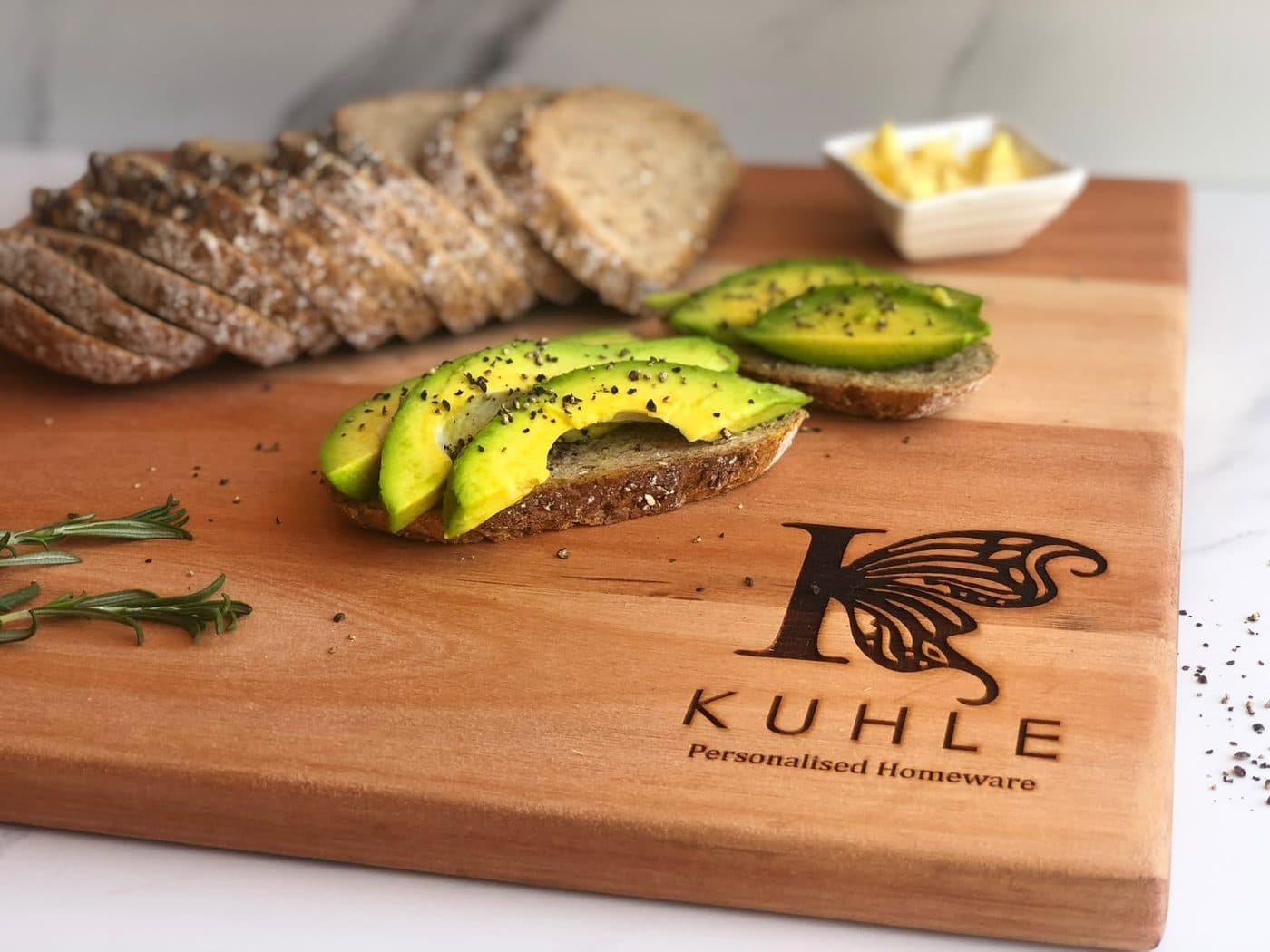 Avocado toast plated on an engraved Kuhle serving board with rosemary