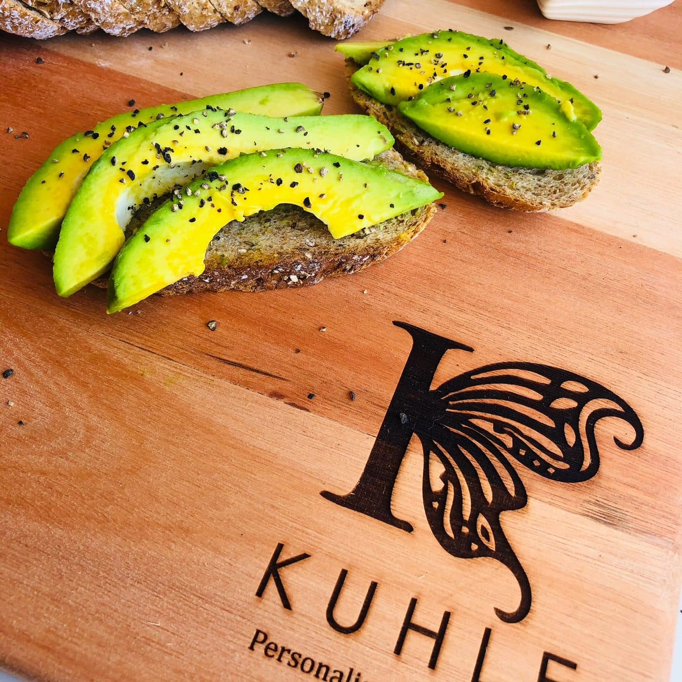 Close-up of the engraved Kuhle butterfly monogram beside avocado toast